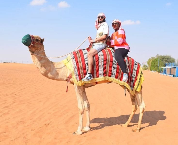 Tourist enjoying camel ride at Abu Dhabi evening desert safari