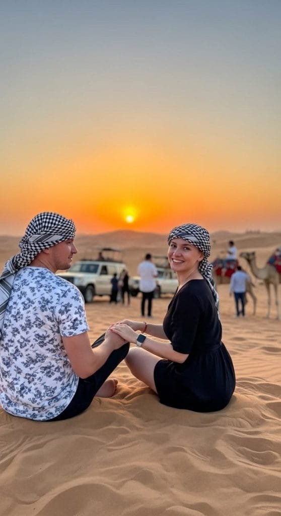 Smiling couple hugging on sand dune at desert safari sunset