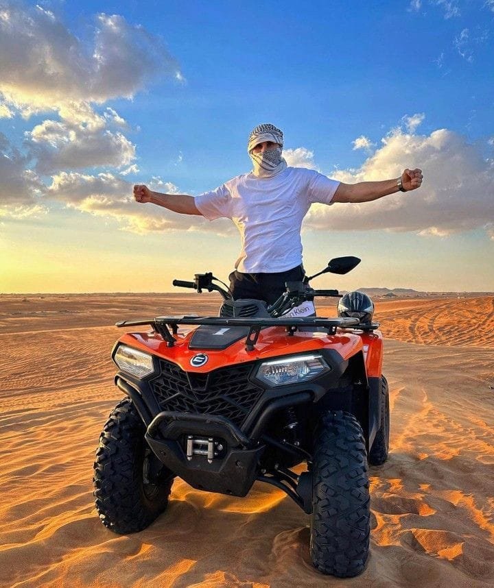 Quad bike photo stop on the crest of a dune at golden hour