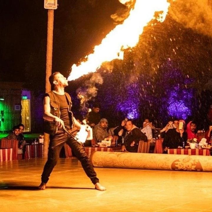 Fire performer holding flaming staff at a desert safari camp