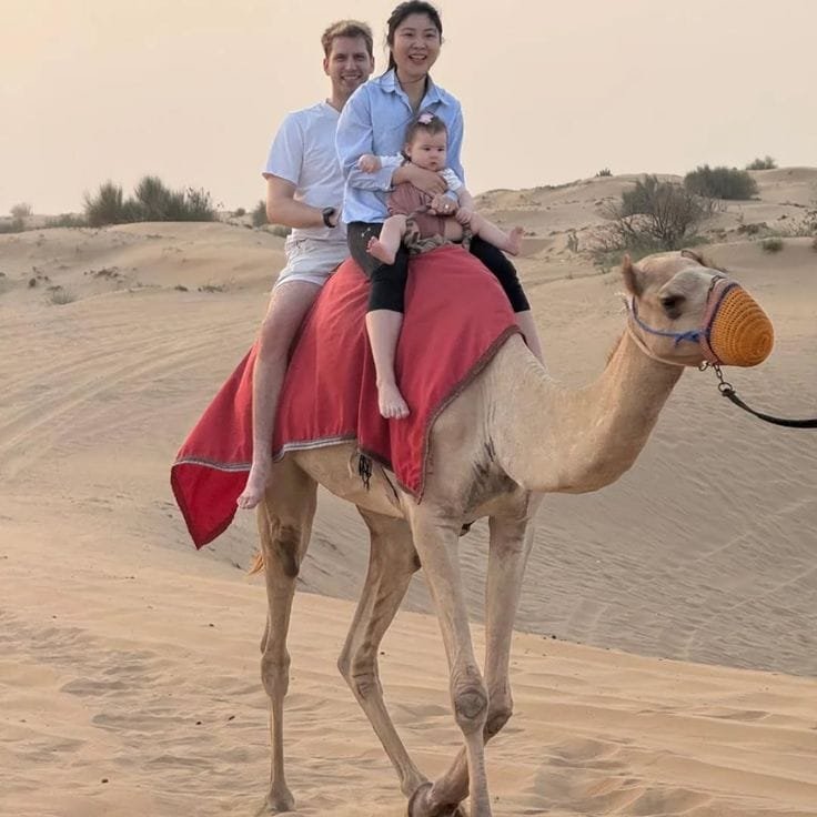A family riding camels together at the Abu Dhabi desert camp