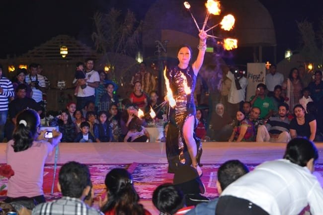 Female fire performer spinning flaming hoops at a desert safari