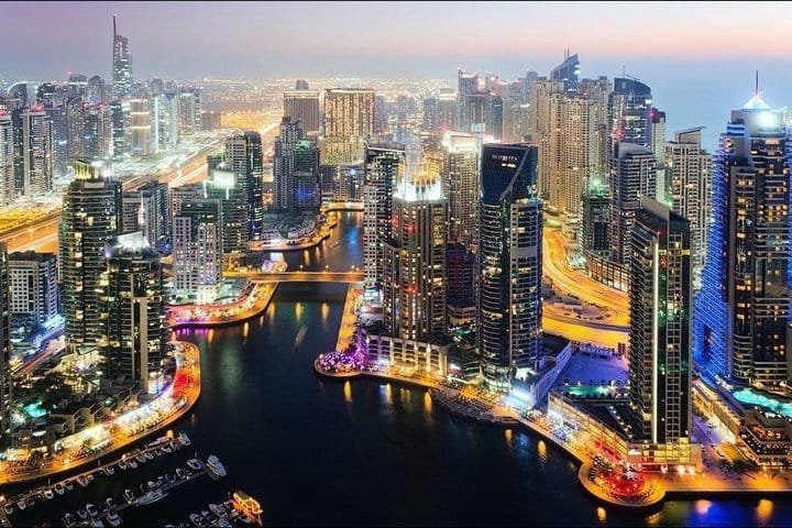 Dubai Marina at night from above, towers and yachts lit along the water