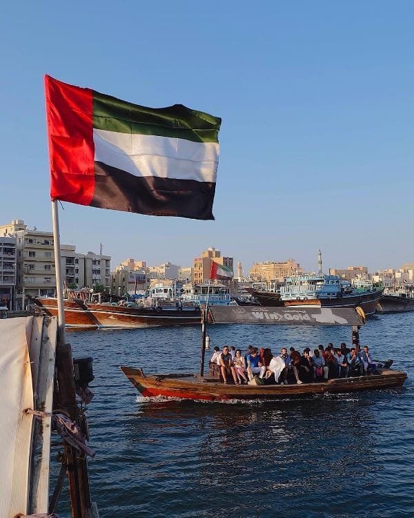 UAE flag flying on an abra water taxi crossing Dubai Creek between Deira and Bur Dubai