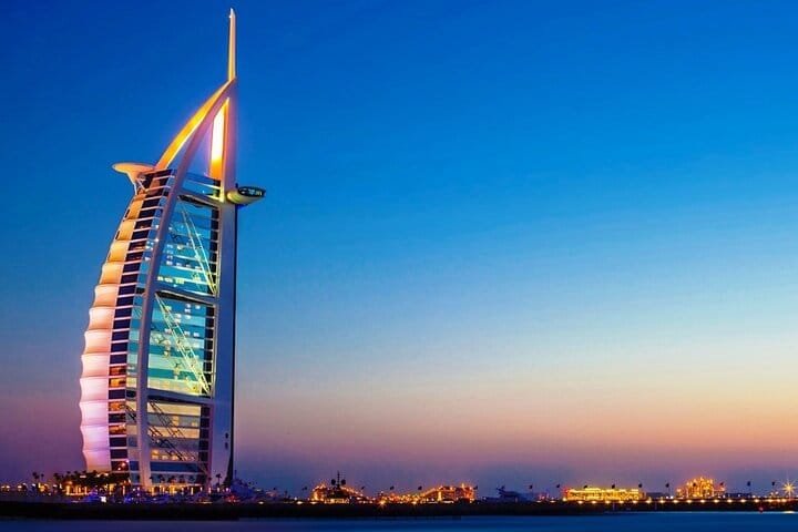 The sail-shaped Burj Al Arab hotel lit at sunset, a photo stop on every Dubai city tour