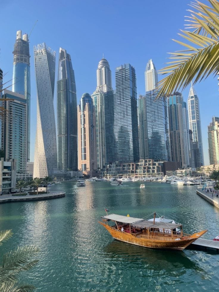 Dubai Marina skyscrapers with a traditional boat on the water
