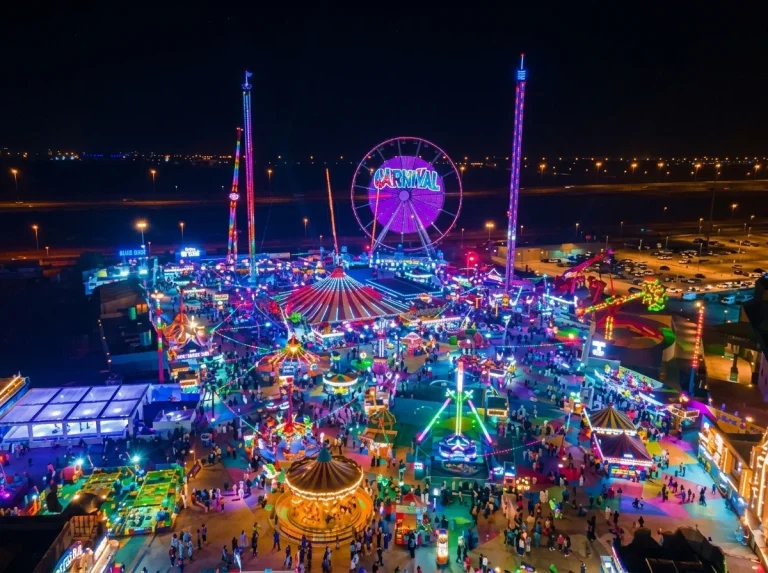 Global Village Dubai carnival rides and Ferris wheel illuminated at night