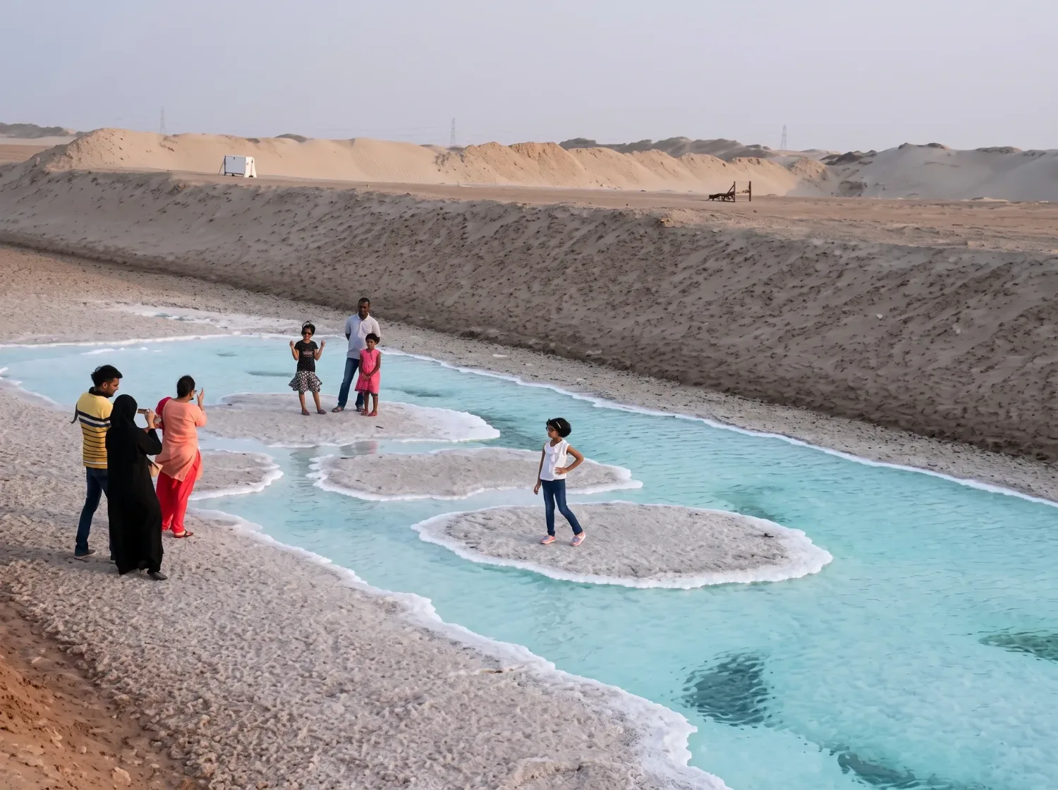 Family with children walking across white salt crusts and turquoise pools at Al Wathba Long Salt Lake near Abu Dhabi