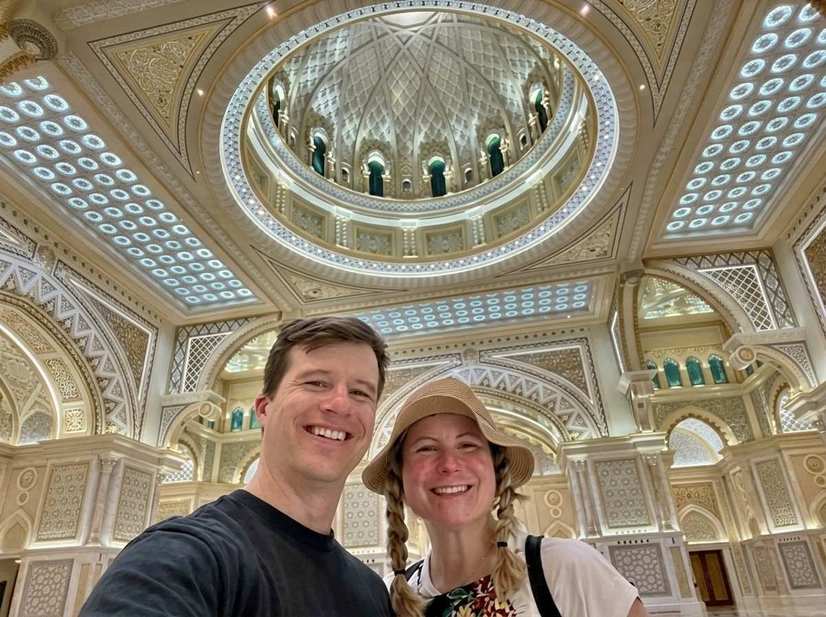 Couple taking a selfie beneath the patterned dome of a palace great hall on an Abu Dhabi stopover city tour