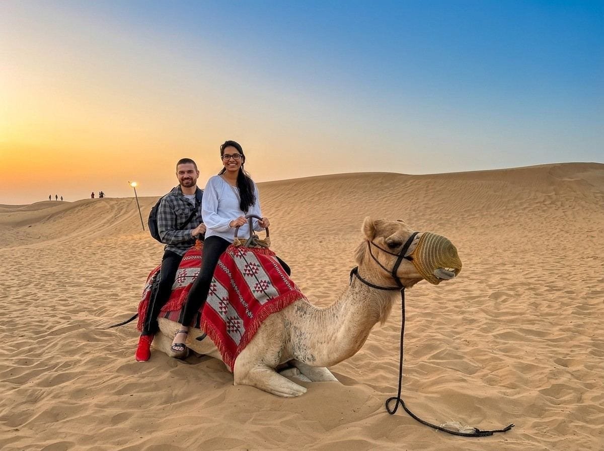 Couple riding a camel across the dunes on an Abu Dhabi stopover desert safari