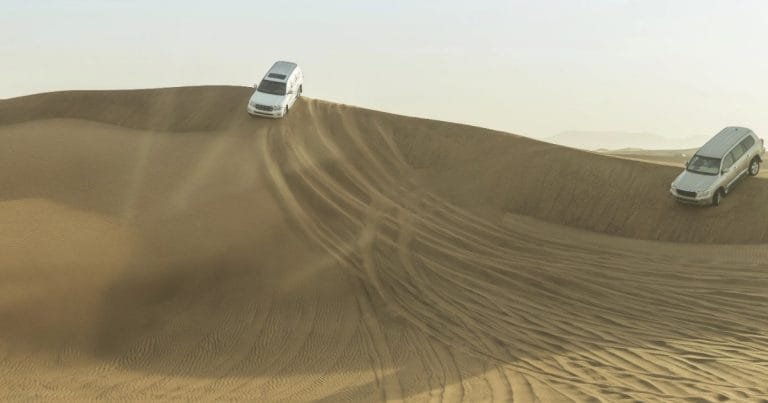 Desert camp beneath the dunes at dusk on an overnight safari in the